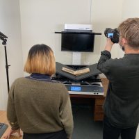 Two people standing in front of a book scanner