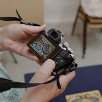 Digital camera held up to show image of embroidery on the display screen.